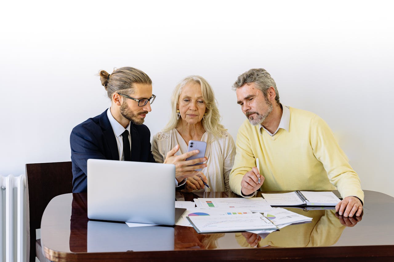 services-04 Three individuals collaborating on financial documents during a business meeting.